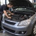 Un mecánico revisa el compartimento del motor de un coche compacto de gasolina
