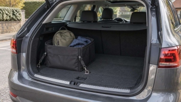 Organizador de tela sujeto en el maletero de un coche, con una mochila pequeña y una chaqueta doblada.